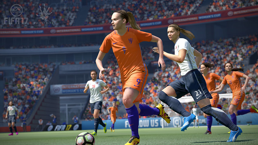Computer game of women's football game, with a female player in orange about the kick the ball.
