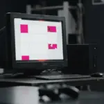 Oude computer en server met een zichtbaar gehackte website in magenta en donkere tinten