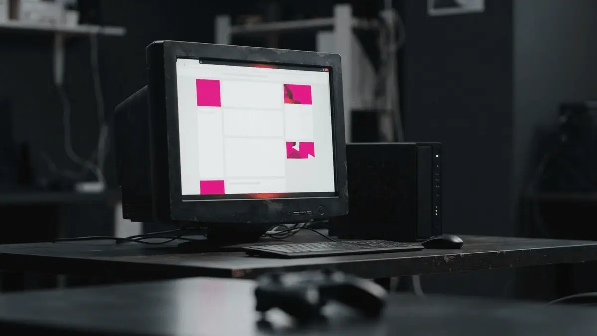 Oude computer en server met een zichtbaar gehackte website in magenta en donkere tinten