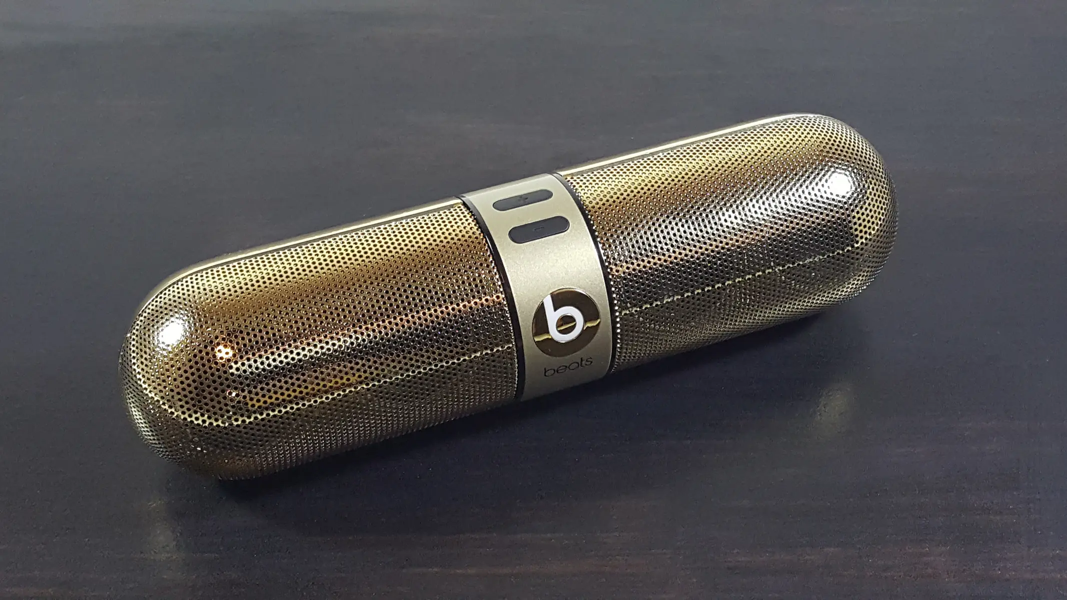 Een goudkleurige Beats Pill draadloze Bluetooth-speaker op een donker oppervlak.