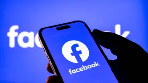 Een smartphone met de Facebook-app op het scherm voor een blauwe achtergrond met het Facebook-logo.