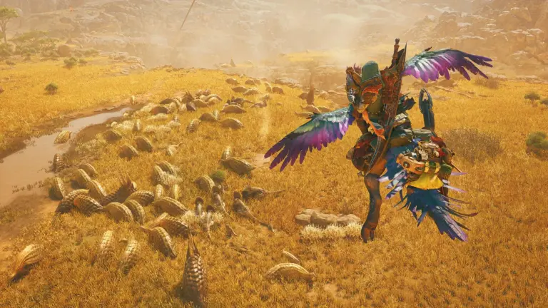 Een jager in kleurrijke bepantsering met vleugels in een zandlandschap met een kudde wezens in Monster Hunter Wilds.